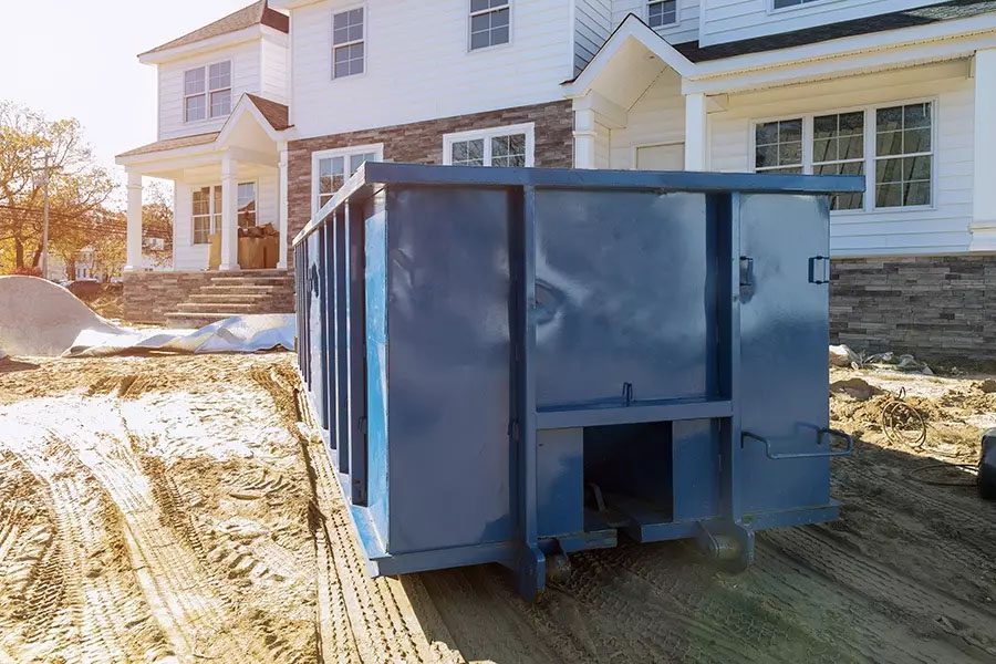 Roll-Off-Contractor-Insurance-Blue-Dumpster-in-Front-of-New-Home-for-Waste-and-Construction-Materials-at-Construction-Site